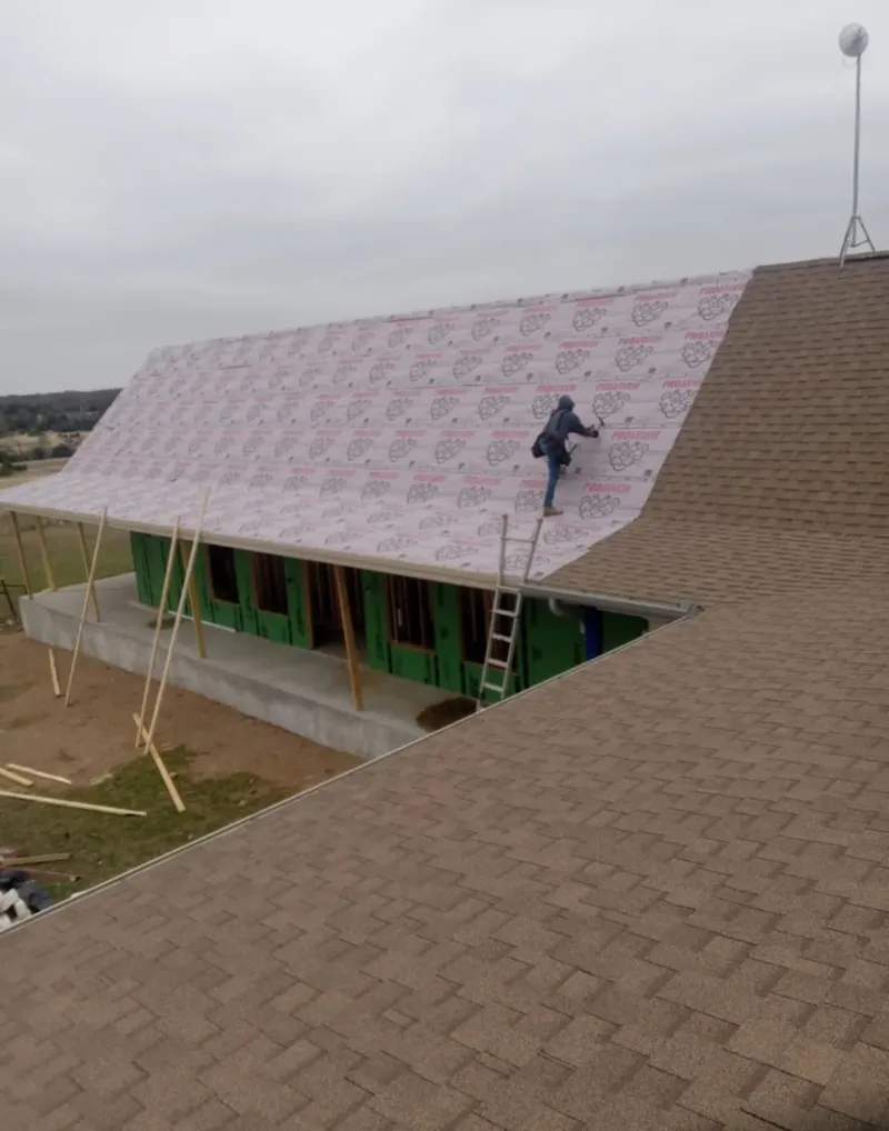 Worker preparing underlayment for a metal roof installation in Clinton